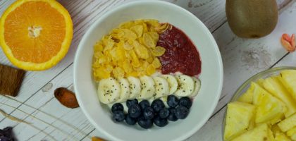 A vibrant breakfast bowl with fresh fruits and cereal on a wooden table.
