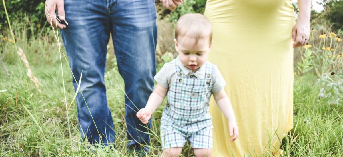 man in black tank top carrying baby in blue and white plaid button up shirt