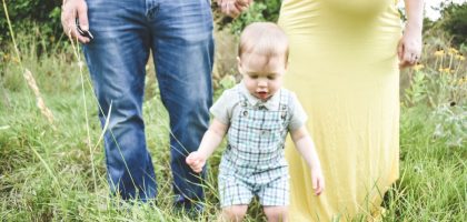 man in black tank top carrying baby in blue and white plaid button up shirt